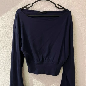 Mörkblå ribbad topp från Ginatricot - Snygg mörkblå ribbad topp från Ginatricot med långa ärmar och en croppad passform. Perfekt för en stilren look.