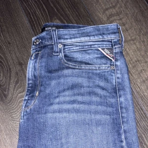 Blå jeans från Replay - Snygga blå jeans från Replay med klassisk femficksdesign och en diskret logga på bakfickan. Jeansen har en bekväm passform och är perfekta för en avslappnad stil. De har en knappgylf och är tillverkade i ett slitstarkt denimtyg. Storlek:158-168cm