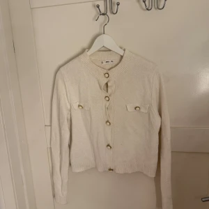 Beige kofta från Mango - Säljer en stilren vit  kofta från Mango med dekorativa vit guldiga knappar framtill. Använd fåtal gånger. Storlek M passar även Xs & S 
