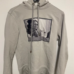 Beige hoodie från Limitato - Säljer en beige hoodie från Limitato med en tryckt bild av Brigitte Bardot på framsidan. Hoodien har en klassisk design med dragsko i huvan och långa ärmar. Perfekt för en stilren och bekväm look.