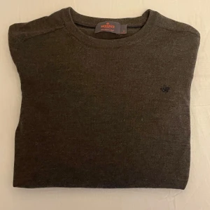 Morris Tröja - Säljer en stilren brun tröja från Morris i 100% merinoull. Tröjan har en rund halsringning och en liten broderad logotyp på bröstet. Perfekt för kyligare dagar! Hör av er om ni har några funderingar!