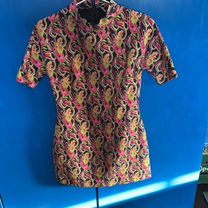 Färgglad kortklänning från Zara - Säljer en färgglad kortklänning från Zara med ett livligt mönster i rosa, gul och svart. Klänningen har korta ärmar och en dragkedja i ryggen. Oanvänd och lappen är kvar från Sellpy. Den är så snygg men passade mig inte riktigt✨