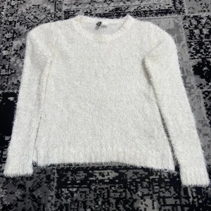 Vit fluffig tröja från H&M Divided - Mysig vit fluffig tröja från H&M Divided. Perfekt för kyliga dagar med sin mjuka och bekväma design. Tröjan har långa ärmar och en rund halsringning.