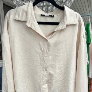 Beige skjorta från Bik Bok - Säljer en stilren beige skjorta från Bik Bok. Skjortan har långa ärmar och knappar framtill. Skjortan är gjord av siden och den är aldrig använd💕💕💕🌸🌸