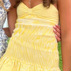 Gul rutig klänning - Söt gul rutig klänning med smockdetaljer och v-ringad hals. 