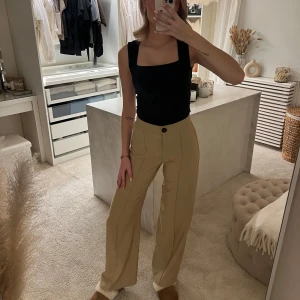Beige byxor från Bershka - Snygga beige byxor från Bershka med hög midja och vida ben. Byxorna har en knapp och dragkedja framtill, även pressveck! Aldrig använda, tyvärr ingen lapp kvar! Jag är 173 cm för referens