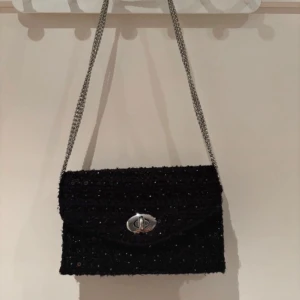 Becksöndergaard väska  - Snygg svart axelväska med glittriga paljetter. Väskan är slutsåld. Har inte använt väskan så mycket. Den är ish i nyskick😃 Väskan har en praktisk stängning framtill och är perfekt för att ge din outfit en extra touch. Perfekt för en kväll ute eller speciella tillfällen.