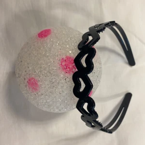 Svart diadem med hjärtformad design - Snyggt svart diadem med hjärtformad design. Perfekt för att ge en söt touch till din outfit. Tillverkad i ett glansigt material som ger en elegant look. Finns fler kvar, samma frakt. Helt ny 
