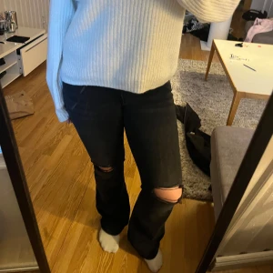 Svarta jeans med slitningar - Snygga svarta jeans med slitningar vid knäna. De har en bootcut-stil och är perfekta för en avslappnad look. Jeansen har en klassisk femficksdesign och är tillverkade i ett bekvämt denimtyg. Jeans med låg midja, använd 2/3 ggr