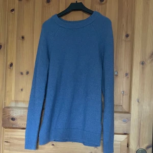 Blå stickad tröja - Säljer en mysig blå stickad tröja med långa ärmar och ribbstickade muddar vid ärmslut och nederkant. Perfekt för kyliga dagar. Passar bra till både jeans och kjol.