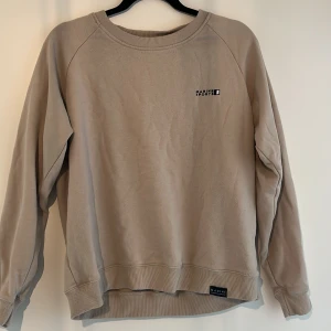 Beige sweatshirt från Marine Sports - Säljer en beige sweatshirt från Marine Sports. Tröjan har en enkel design med en liten logotyp på bröstet. Den är långärmad och har ribbade muddar vid ärmslut och nederkant. Perfekt för en avslappnad stil.