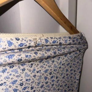 Blommig kjol🩷 - Blommig kjol från Pull and bear i en mjuk beige nyans med blå blommor. Kjolen har en tajt och lång passform.(Kjolen ser lite bred ut på bilden och inte så tajt ut men det är pågrund av galjen) Kjolen har även en gullig rosett fram till, skriv om det finns frågor och priset kan alltid diskuteras❤️❤️ Den är även helt ny men utan lapp! Så inga defekter finns på kjolen!