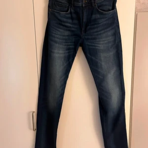 Mörkblå Hugo boss jeans - Snygga mörkblå jeans med en klassisk straight passform. De har en midwaist design och är perfekta för en avslappnad stil. Byxorna har en dragkedja och knappar framtill samt fickor både fram och bak.
