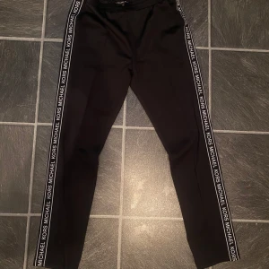 Svarta byxor från Michael Kors - Michael kors mjukis i storlek M. Den är i ett väldigt bra skick och materialet är av polyester som är ett glansigt och sportigare material.