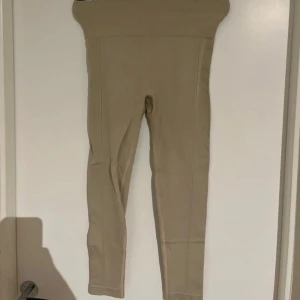 Beige seamless leggings med hög midja - Säljer ett par beige seamless leggings med extra hög ribbad midja och scrunch-detalj bak. De är tighta och stretchiga, perfekta för träning eller chill. Materialet är mjukt och följsamt.