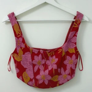 Blommig croppad topp från Zara - Säljer en färgglad croppad topp från Zara med blommigt mönster i rosa och gult. Toppen har breda axelband och figurnära passform, perfekt för sommardagar.