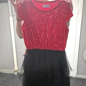 Röd paljettklänning med svart tyllkjol - Säljer en glittrig röd paljettklänning.