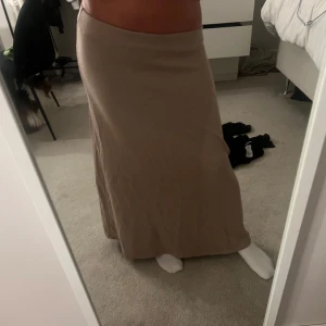 Beige långkjol i stickat material - Säljer en beige långkjol som tillhör ett set i mjukt stickat material. Kjolen har en rak och enkel design med resår i midjan för en bekväm passform. Perfekt för dig som gillar en stilren och avslappnad look. I storlek M men passar mig som brukar ha S och XS ibland. helt ny aldrig använts