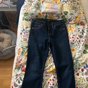 True Religion Becca Mid Rise Bootcut Jeans - Säljer mörkblå populära jeans från True Religion, modell Becca Mid Rise bootcut. Aldrig använda! Säljer för att de sitter lite tajt på mig. Storlek 26 men kan passa dig som har storlek 25!