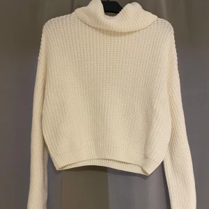 Vit stickad polotröja - Säljer en vit stickad polotröja med lång ärm och hög, bred krage. Enkel och stilren design som passar till det mesta. 