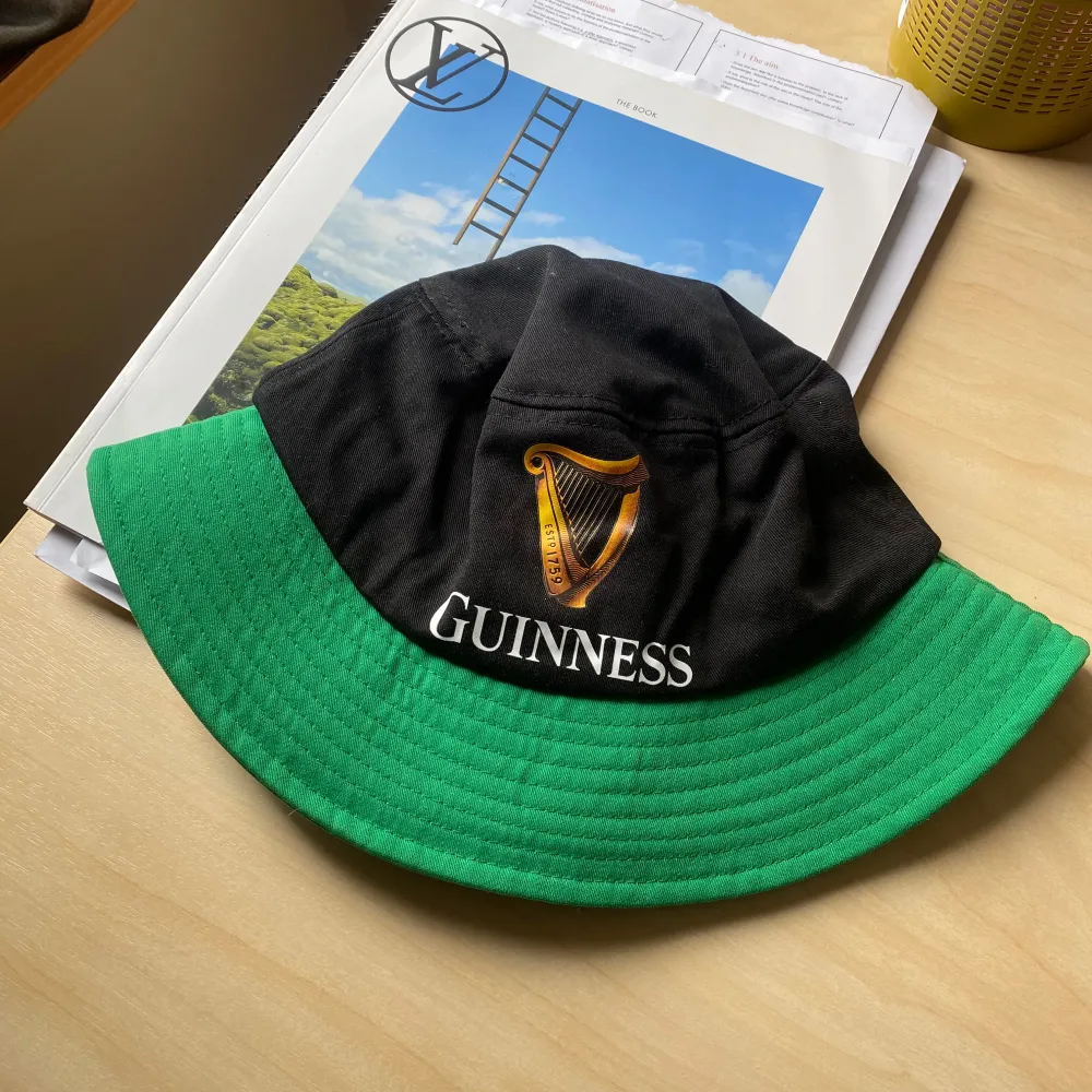 Bucket hat i svart och grönt med Guinness-logga och harpa broderad framtill. Klassisk form med bred, nedvikt brätte. Perfekt accessoar för dig som gillar ikoniska märken och vill sticka ut. ONE SIZE. Asusteet.