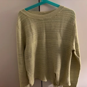 Ljusgul ribbad tröja från MNG - Säljer en ljusgul ribbad tröja från MNG med lång ärm och knytdetalj nertill. Tröjan har en rund halsringning och är tillverkad i ett mjukt, stickat material. Perfekt för dig som gillar en enkel men snygg stil.