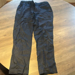 Mörkblå linnebyxor från Zara - Säljer ett par mörkblå linnebyxor från Zara i storlek M. Byxorna har klassisk rak passform med hällor för bälte och stängs med dragkedja och knapp. Perfekta för varmare dagar tack vare det svala linnematerialet.