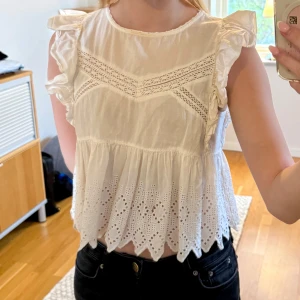 Vit blus med spetsdetaljer från Zara - Säljer en söt vit blus från Zara med volangärmar och broderade spetsdetaljer. Blusen är i storlek xs.