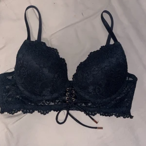 Svart spets bralette med snörning - Säljer en svart bralette med spetsdetaljer och pydnings-snörning framtill. Modellen har tunna axelband och vacker spetskant nedtill. Perfekt för att ge en extra touch till din outfit.