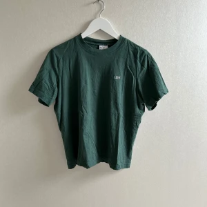 Grön t-shirt  - Mörkgrön t-shirt från Divided med liten vit broderad text 'LOVE' på bröstet. Klassisk rund halsringning och korta ärmar. Tillverkad i mjuk bomull💗