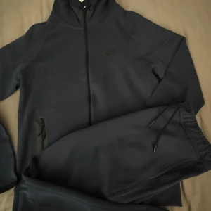 Mörkblå mjukisbyxor från Nike - Hej säljer Nike Tech Tracksuit som är alldrig använt. Den är i färgen mörk blå och är jätte fin outfit. Passa på och köp för dem är snart slut. Storlek S och M är tyvärr sålda men finns i L XL XXL
