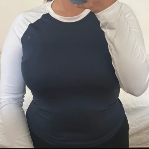 Blå och vit långärmad topp från SHEIN - Säljer en långärmad topp från SHEIN i marinblått med vita ärmar och krage. Tillverkad i stretchigt material med 95% polyester och 5% elastan. Perfekt för en sportig och avslappnad stil.