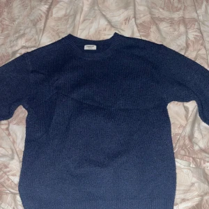 Mörkblå stickad tröja från Kappahl - Enkel och snygg mörkblå stickad tröja från Kappahl. Tröjan har rund halsringning och långa ärmar, perfekt för kyligare dagar. Passformen är normal och materialet känns mjukt och bekvämt mot huden. Stilren och lätt att matcha med det mesta.