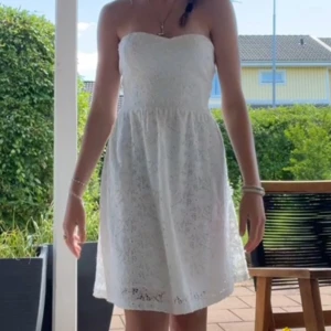 Vit axelbandslös spetsklänning - Superfin vit kortklänning i spets med axelbandslös design och hjärtformad urringning. Den har en open back design. Jag har sytt om den från M/L till S.