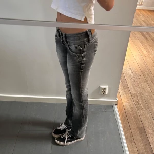 Lågmidjade jeans  - Säljer ett par gråa jeans med snygg tvätt och slitningar. Jeansen har låg midja, raka ben och klassiska fickor både fram och bak. De är i bomull och har en stilren look som passar till sneakers eller boots.