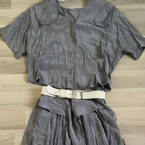 Vintage set med vit bälte - Säljer en grå/silver Vintage set. Vintage kjolen kommer med egen vit bälte. Materialet är silke.