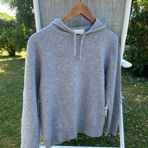 Grå kashmirhoodie från Sayless - Mjuk och lyxig grå hoodie från Sayless i kashmir. Klassisk modell med huva och snörning, ribbade muddar och lång ärm. OBS!! det står storlek M i tröjan men den sitter som en storlek S! Tveka inte att höra av dig vid fler bilder eller frågor! 
