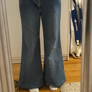 Blå wide jeans från Bianco Jeans - Säljer ett par blå jeans från Bianco Jeans med snygga diagonala sömmar på benen. Jeansen har en wide passform och är tillverkade i bomull med lite stretch. Perfekta för dig som gillar en avslappnad och trendig look.