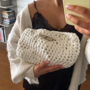 Vit stickad handväska - 🤍Superfin handväska i chunky stickad design.                                                                        Väskan har inbyggt handtag och en mjuk, rektangulär form som rymmer både bok och småprylar. Perfekt accessoar för dig som gillar unika detaljer och en clean look. Mått: B:33cm H:18 cm