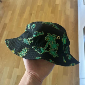  bucket hat Vans - Cool svart bucket hat från Vans med tropiskt mönster i grönt och gult. Använd 1 gång