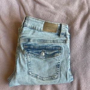 Low waist bootcut Gina Tricot jeans - Ljusblåa low waist bootcut Gina Tricot jeans med y2k bakfickor. Lite använd men inga stora tecken från användningen