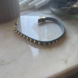 Blått armband med guldnitar från Edblad - Jättefint armband från Edblad, det är i blått och guld med nitar. Tyvärr har armbandet blivit lite repigt på insidan av knäppet, men inget som märks💗💗 