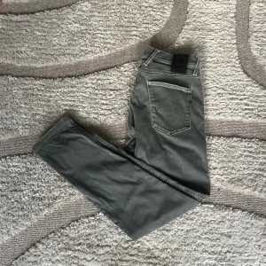 Reaplay hyperflex - Snygga grå jeans från Replay i modellen Anbass. Dessa jeans har en slim passform och är tillverkade i det bekväma Hyperflex-materialet. Perfekta för en stilren look med broderad detalj på bakfickan. Storlek  W 30 L32