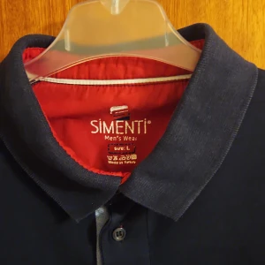 Mörkblå pikétröja från Simenti, L - Snygg mörkblå pikétröja från Simenti i storlek L. Klassisk modell med krage och knappar framtill. Tillverkad i mjuk bomull, perfekt för en clean och stilren look. Passar dig som gillar enkel och tidlös stil.