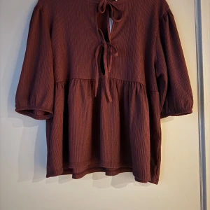 Vinröd blus med knyt, helt ny!  - Säljer en vinröd blus från lager157 i storlek M. Blusen har en loose passform, trekvartsärmar och snygga knytband framtill. Helt ny med prislapp! 