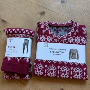 Vinröd Stella termotröja och leggings - Mysig vinröd termotröja från Stella med vita snöflingor, hjärtan och diamantmönster. Långärmad och perfekt för kalla dagar. Tillverkad i mjukt och varmt material som håller dig bekväm hela vintern.