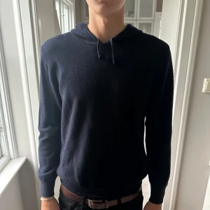 Mörkblå kashmirhoodie från Sayless - Mjuk och stilren mörkblå hoodie från Sayless i kashmir. Tröjan har huva med snörning och långa ärmar. Perfekt för dig som vill ha en enkel men exklusiv look. Passar till både jeans och chinos. Säljer då den är för liten. Modellen är 194cm 82kg. Hör av er vid frågor!