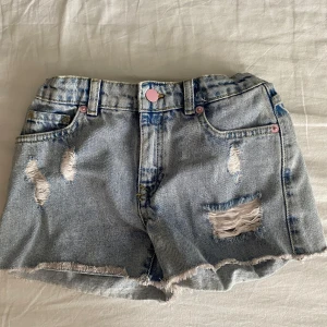 Ljusa jeansshorts med rosa detaljer från Zara Kids - ljusblå jeansshorts från Zara Kids med slitna detaljer. rosa knapp och justerbar midja på insidan.  