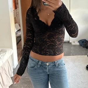 Svart spetsblus med v-ringning - Supersnygg och populär svart långärmad spetsblus från Gina Tricot med v-ringad hals och croppad passform. Perfelt till finare tillfällen och fest!