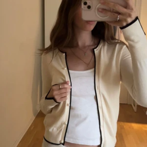 Beige kofta med svarta detaljer från Zara - Superfin beige kofta från Zara med svarta detaljer och pärlknappar. Långärmad och i mjukt, tunt material. Tröjan har knappast använts och är i jättebra skick! Storlek: S 💕💕